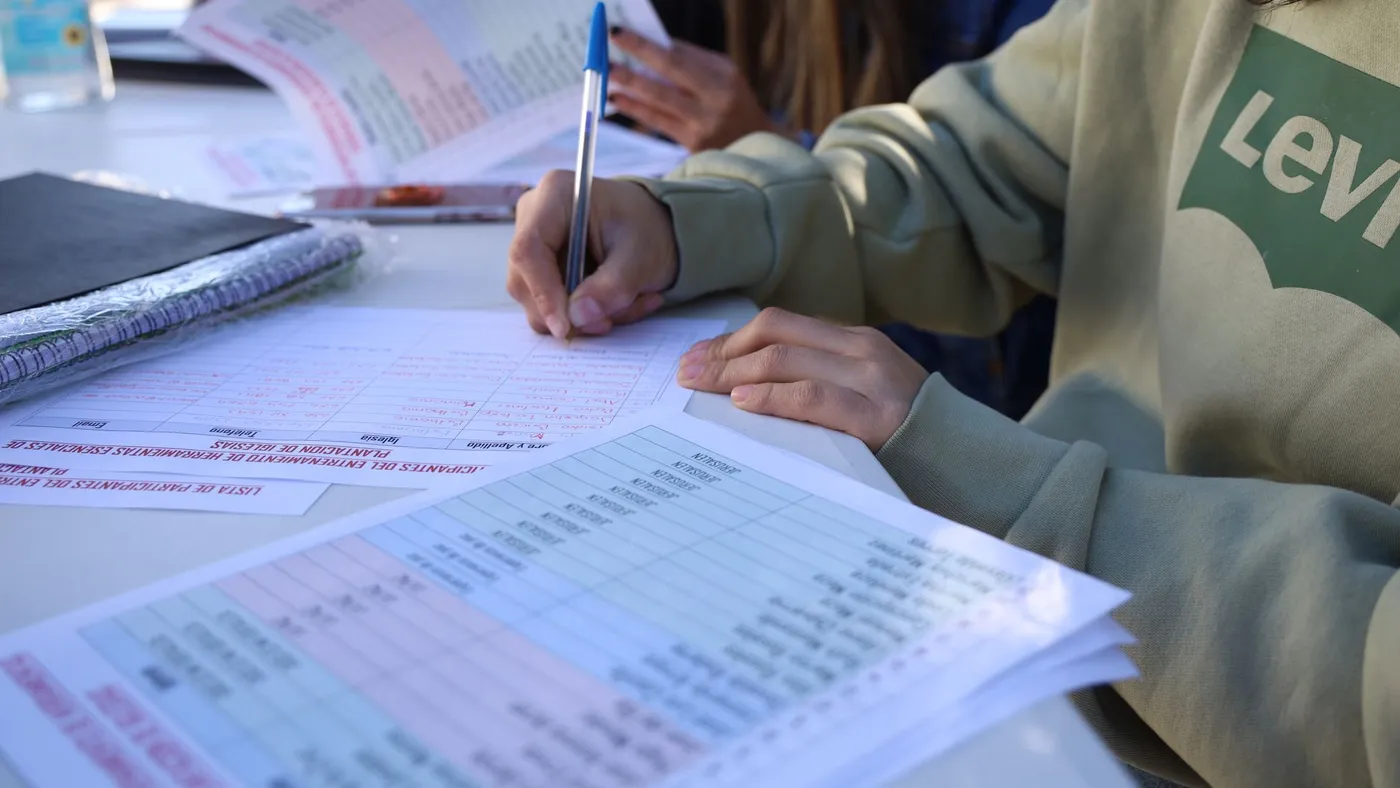 Renkli materyallerin bulunduğu masada planlama yapan eğitimcilerin elleri